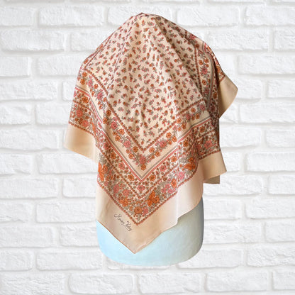Decorative scarf with floral pattern on a mannequin against a white brick wall.