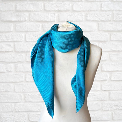 Blue patterned scarf on a mannequin against a white brick wall background 