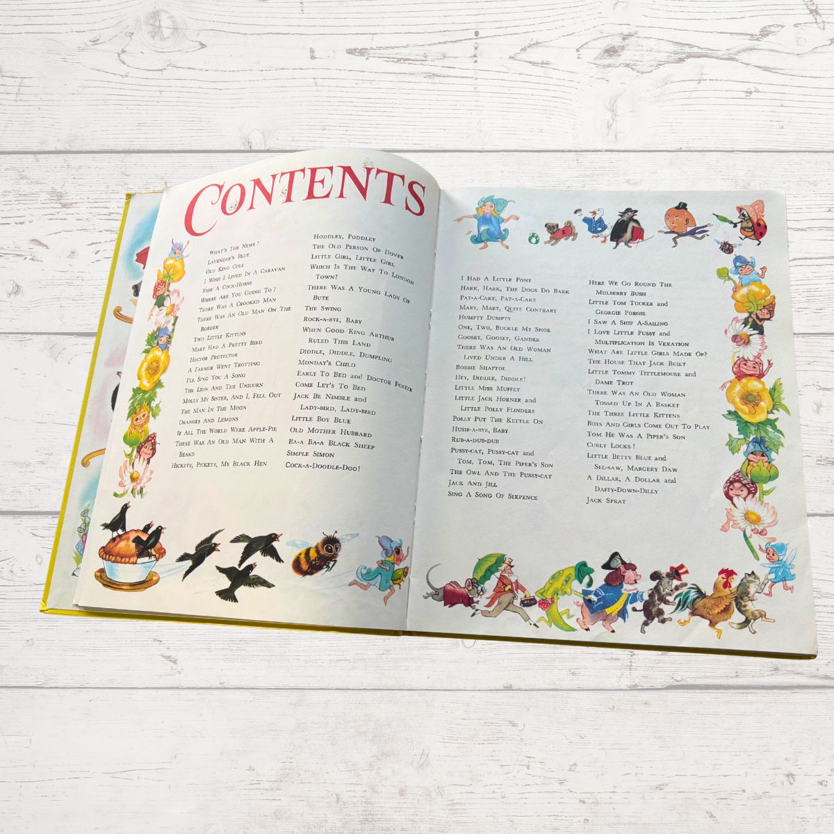 Open book with colorful illustrations on a white wooden surface