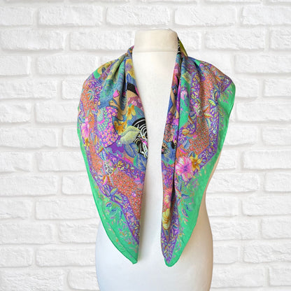 Colorful floral and patterned scarf on a mannequin against a white brick wall.