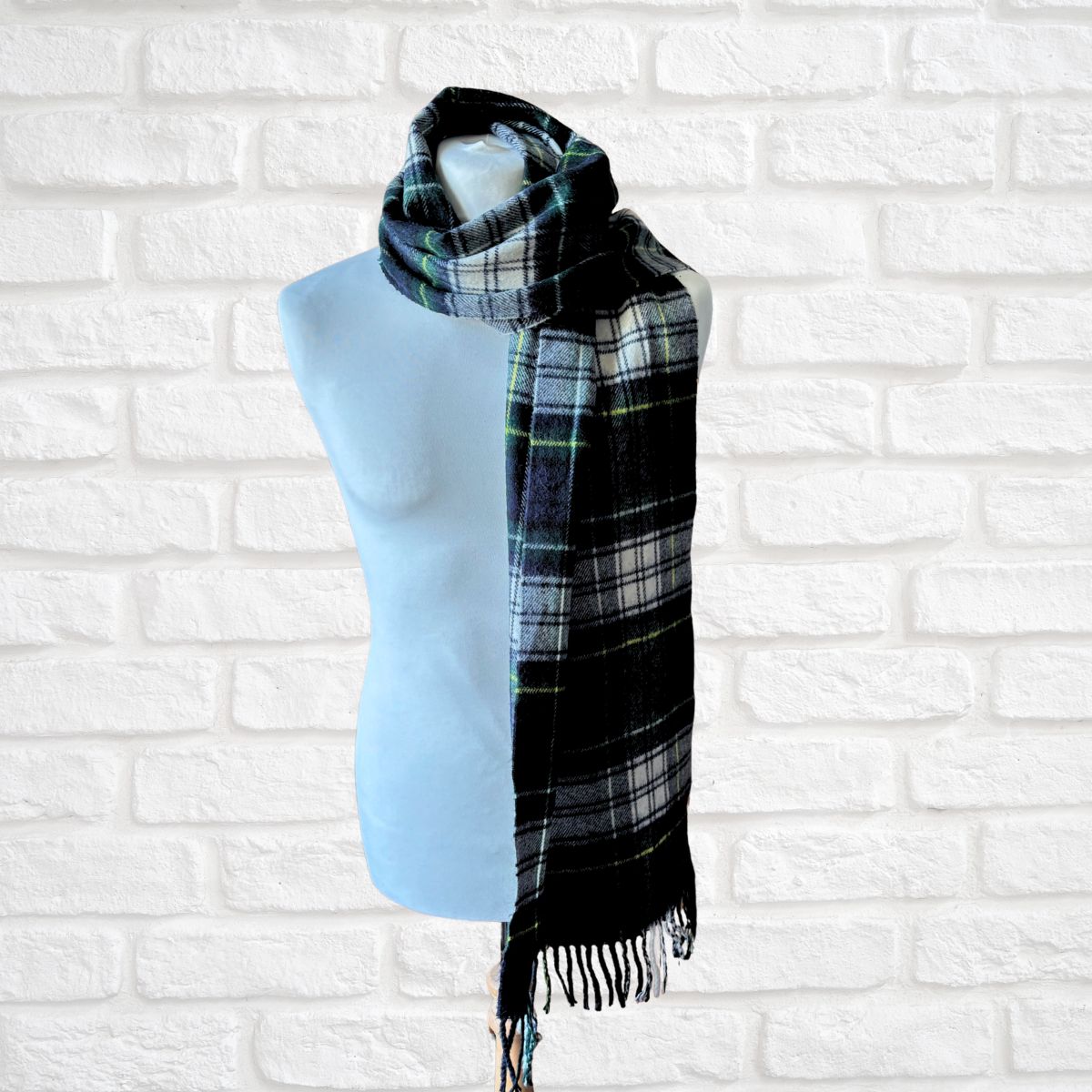 Plaid scarf on a mannequin against a white brick wall background