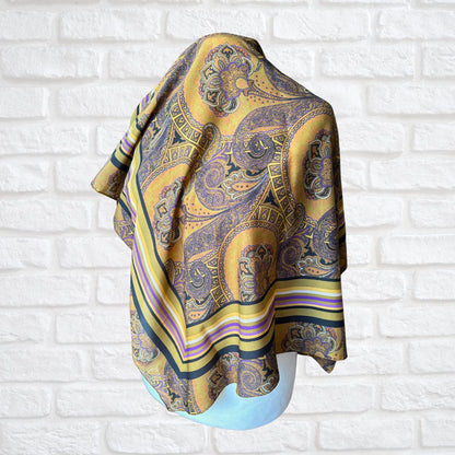 Patterned scarf draped over a mannequin against a white brick wall.