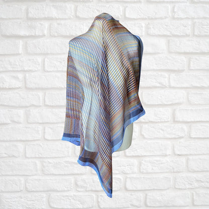 Semi sheer silk scarf  draped over a mannequin against a white brick wall.