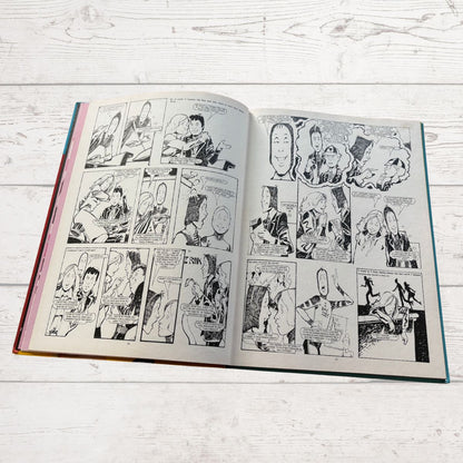 Open book with comic strip on a light wooden surface