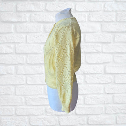 Light yellow knitted sweater on a mannequin against a white brick wall background