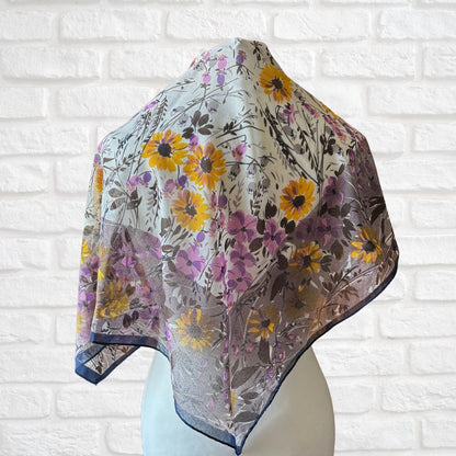 Floral patterned scarf on a mannequin against a white brick wall background