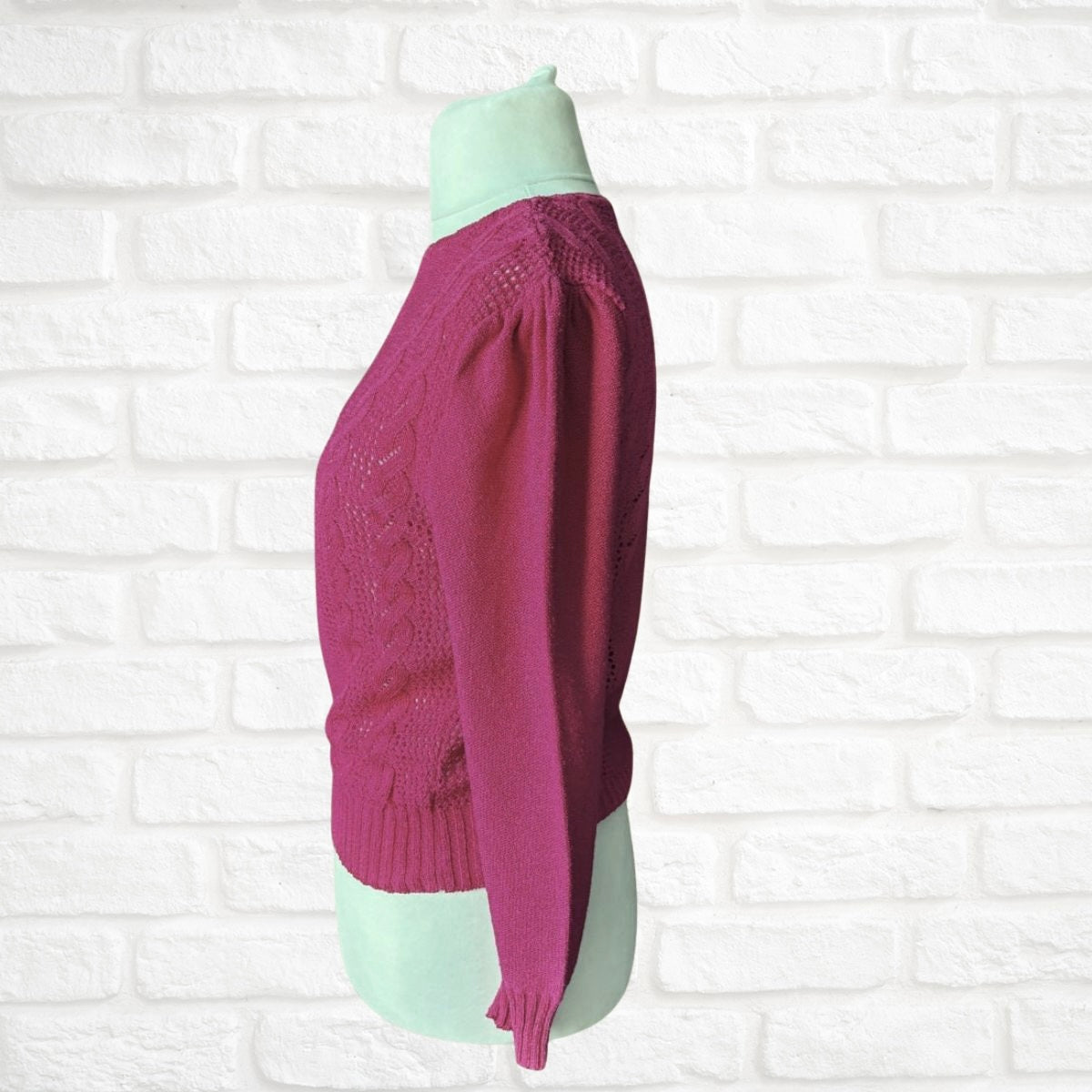 Pink sweater on a mannequin against a white brick wall background