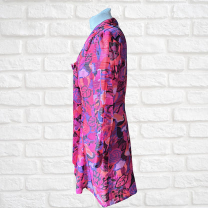Colorful floral dress on a mannequin against a white brick wall background