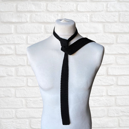 Black knitted tie on a mannequin against a white brick wall background