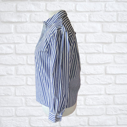Blue and white striped shirt on a mannequin against a white brick wall background