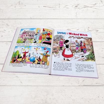An open vintage children's book  spread laid flat on a white wood surface. The left page contains four cartoon comic panels, and the right page has a large illustrated cover titled 'Lorna the Wicked Witch' with text below.