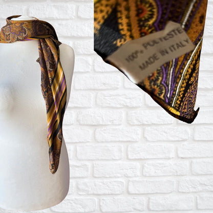 Patterned scarf on a mannequin with 'Made in Italy' label against a white brick wall.