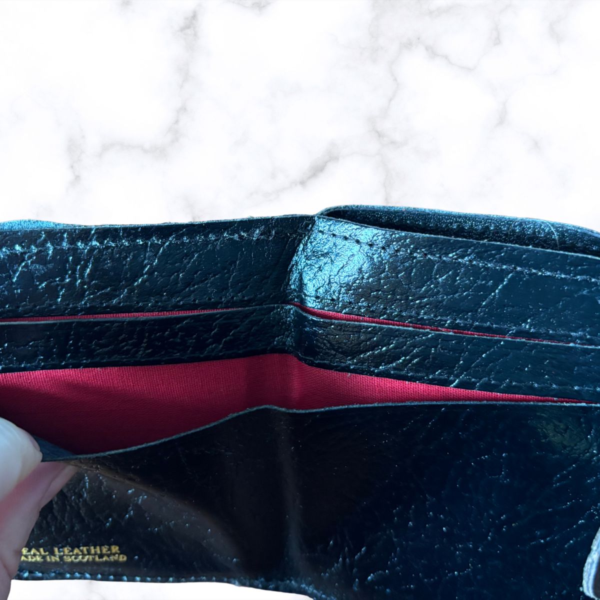 Black leather wallet with red interior on a white background