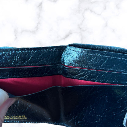 Black leather wallet with red interior on a white background