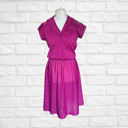 Pink dress with white polka dots on a mannequin against a white brick wall background