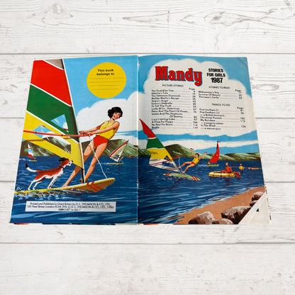 Open book titled 'Mandy' with illustrations of a woman windsurfing on a beach.