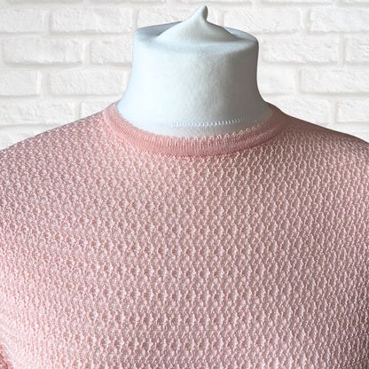 A light pink textured knit dress displayed on a white mannequin torso against a white brick wall background.