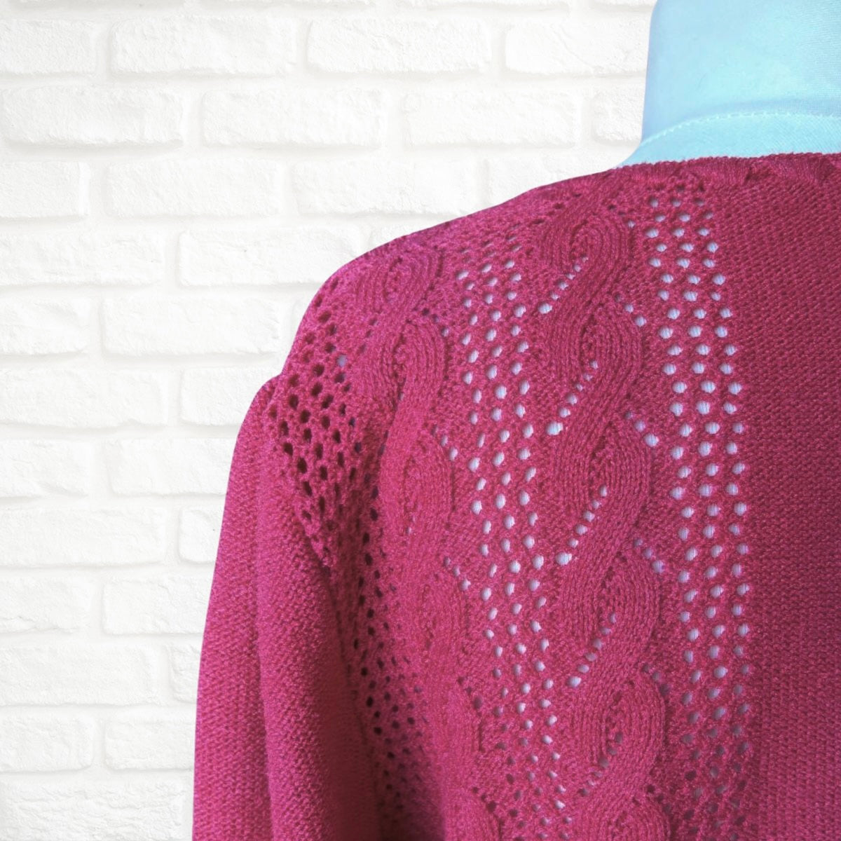Close-up of a pink knitted sweater with a textured pattern on a white background