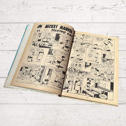 Open comic book with black and white illustrations on a light wooden surface