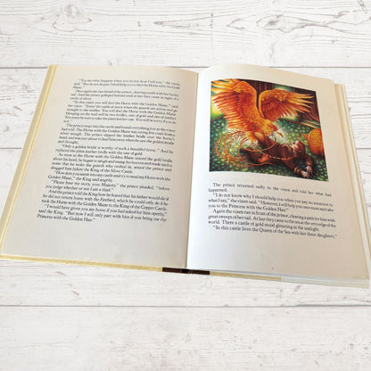An open children's picture book lying on a light whitewashed wooden surface. The left page has printed text, and the right page shows a colorful illustration of a golden horse with a rider.