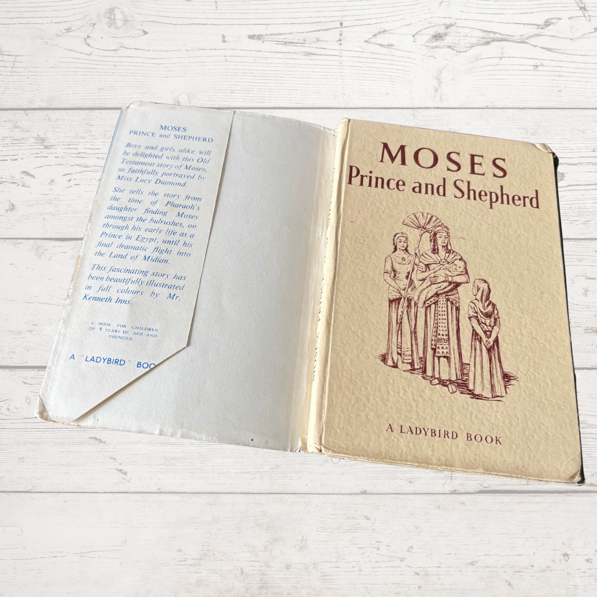 Open book titled 'Moses Prince and Shepherd' by A Ladybird Book on a wooden surface