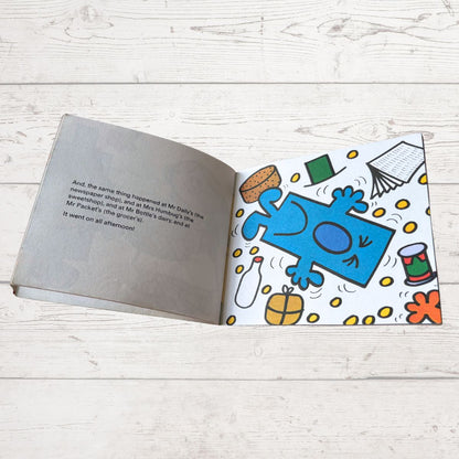 Open book with a colorful illustration of a blue character on a white wooden surface