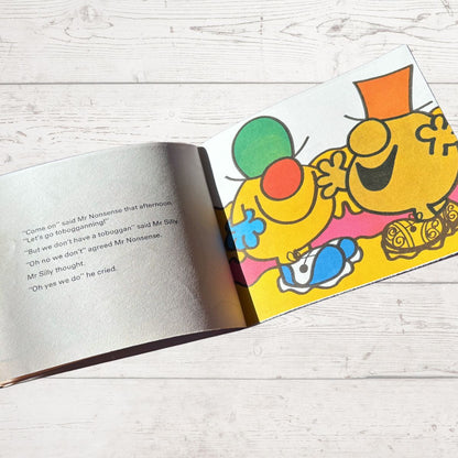 Open book with colorful cartoon characters on a wooden surface