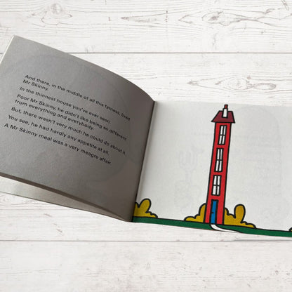 Open book with a drawing of a red lighthouse on a white wooden surface