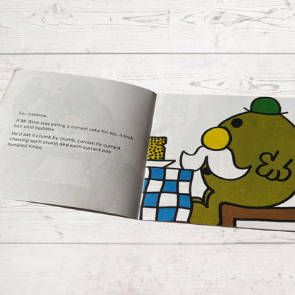 Open book with a cartoon character sitting at a table on a wooden surface