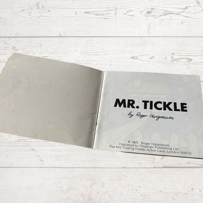 Open book with 'MR. TICKLE' title on a wooden surface