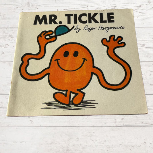 Book cover of 'Mr. Tickle' by Roger Hargreaves on a wooden surface