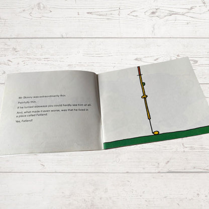 Open book with text and a drawing of a thin stick figure on a wooden surface