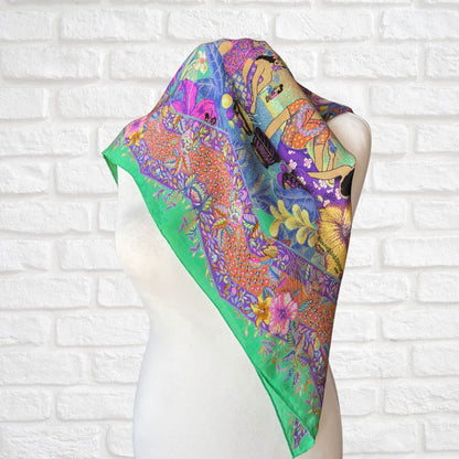 Colorful scarf with floral and abstract designs on a mannequin against a white brick wall.