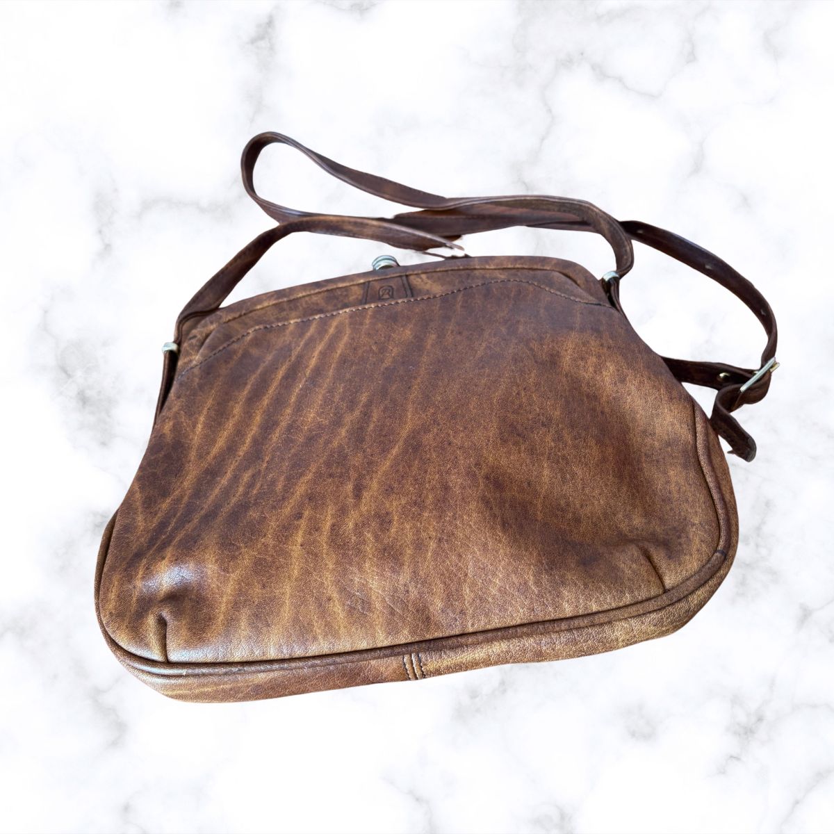 Brown leather look bag on a white marble background