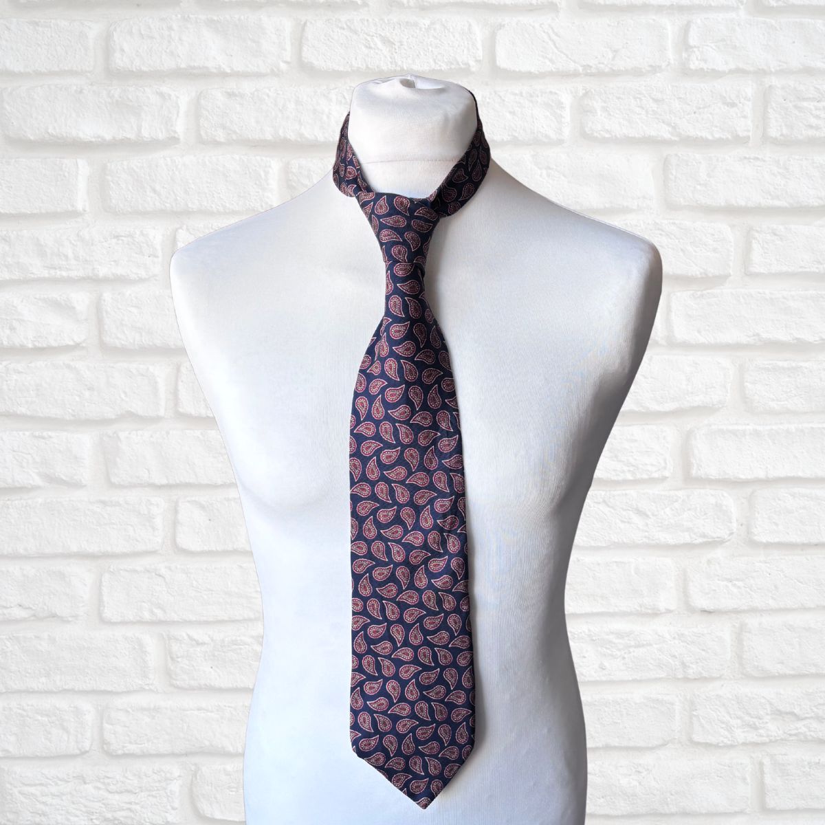 Navy and Red Paisley Silk Vintage Tie On a white brick background 