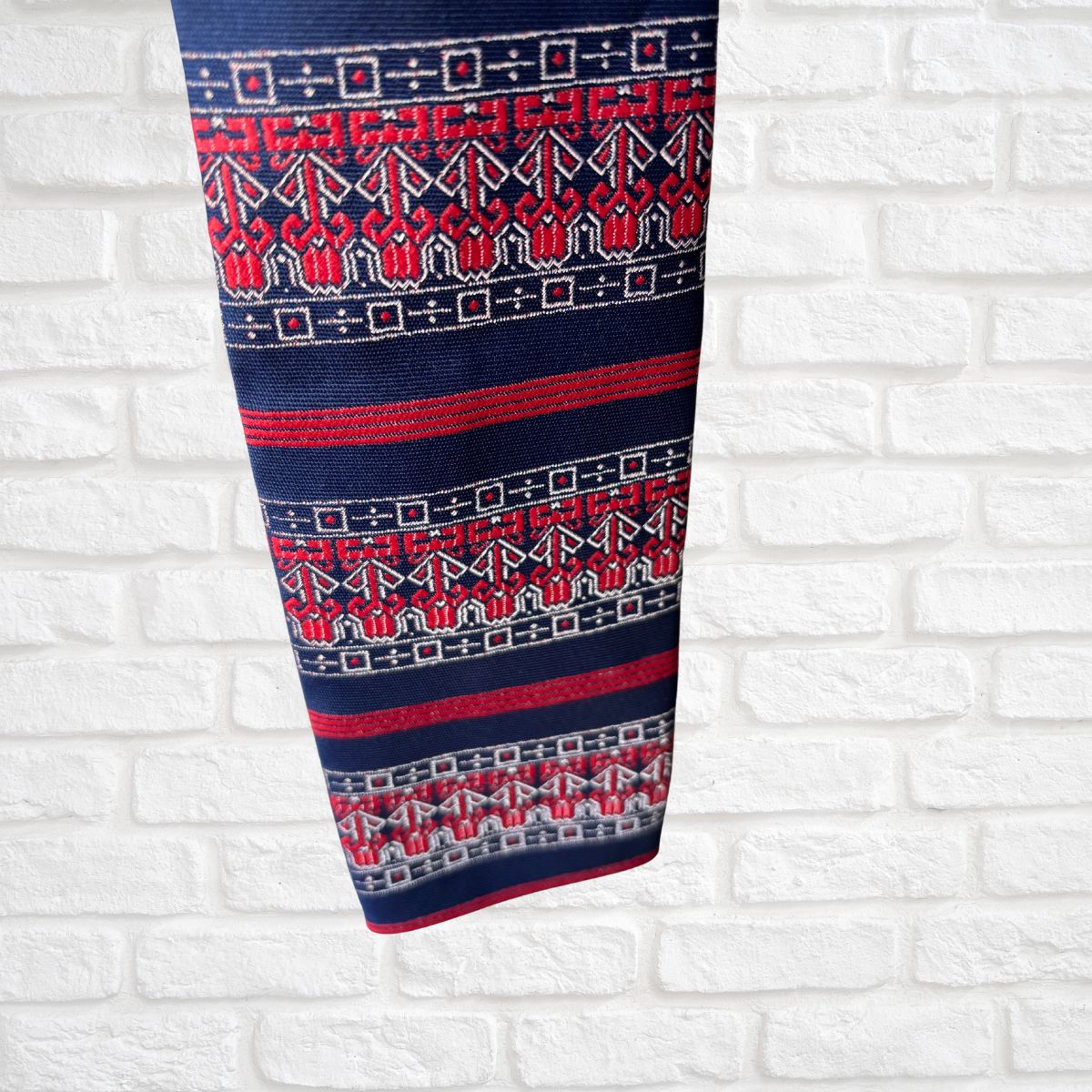 Red  and  blue patterned tie  on a white brick wall