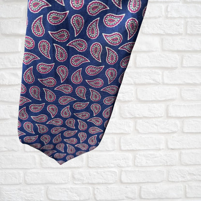 Navy and Red Paisley Silk Vintage Tie On a white brick background - close up 