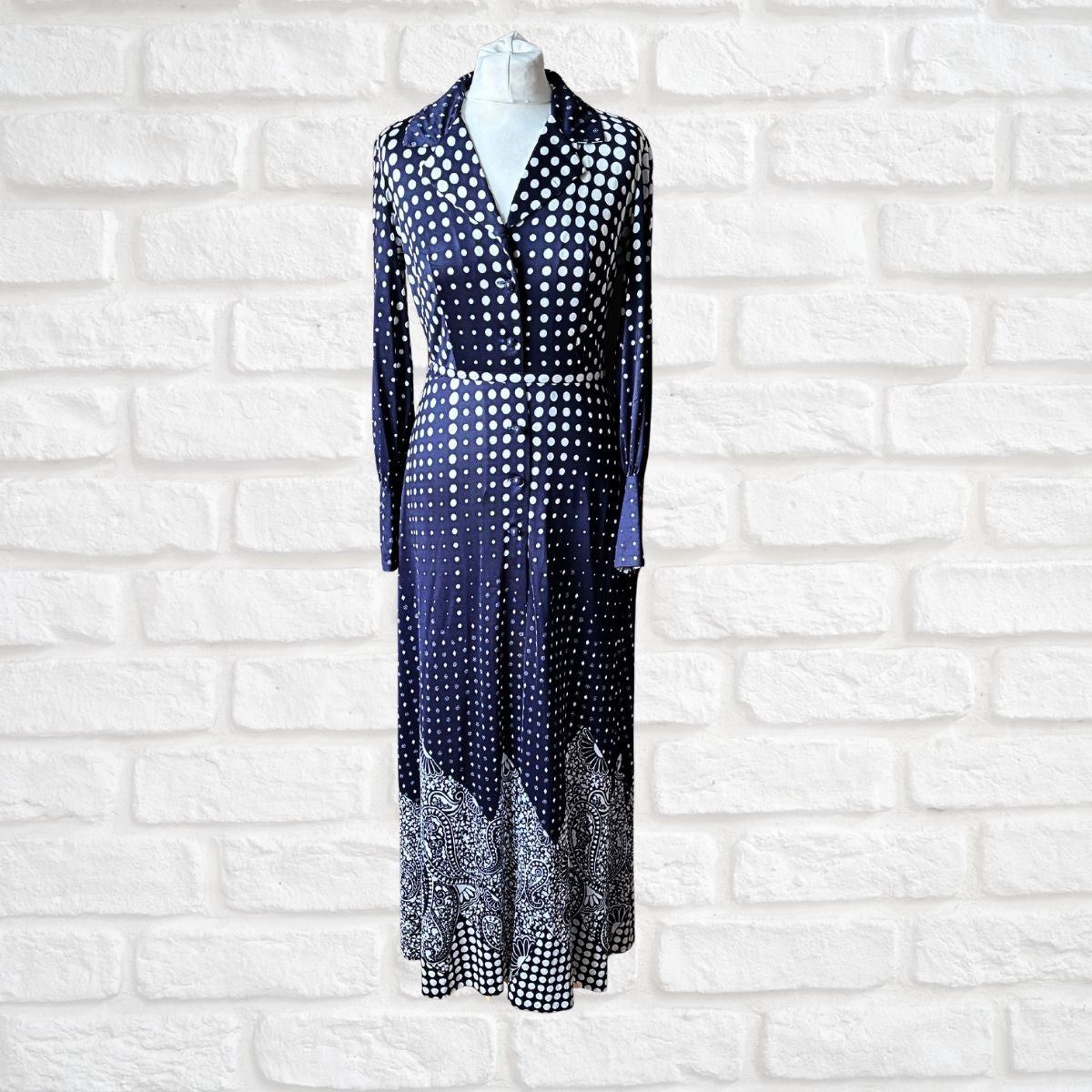 Navy blue and white long length polka dot 70s dress On a white brick background 