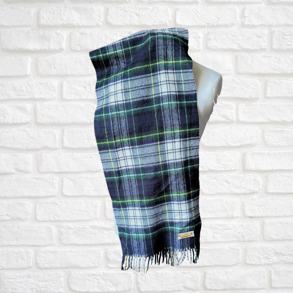 Plaid scarf on a mannequin against a white brick wall background