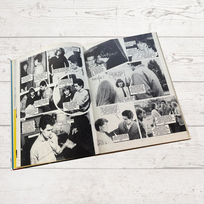 Open book with black and white comic-style pages on a light wooden surface