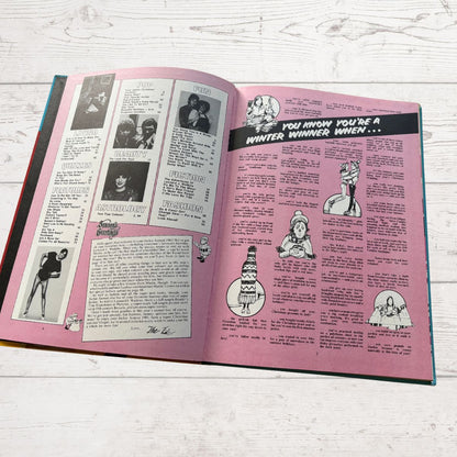 Open book with pink pages featuring text and black and white illustrations on a light wooden surface