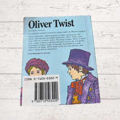 Back cover of 'Oliver Twist' book with illustrations and text on a light wooden surface