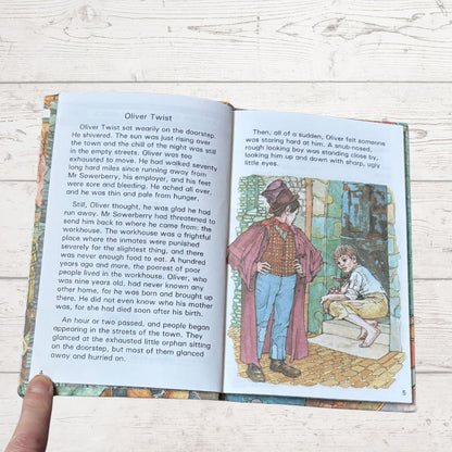 Open book with text and illustration of a scene from 'Oliver Twist' on a wooden surface.