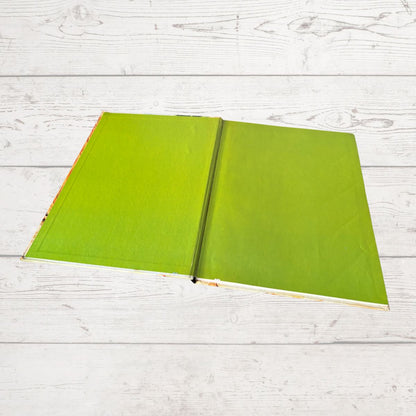 Open green book on a light wooden surface