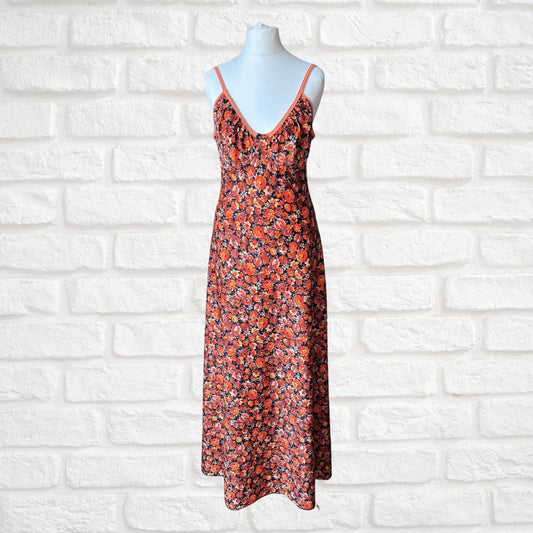 Floral maxi dress on a mannequin against a white brick wall