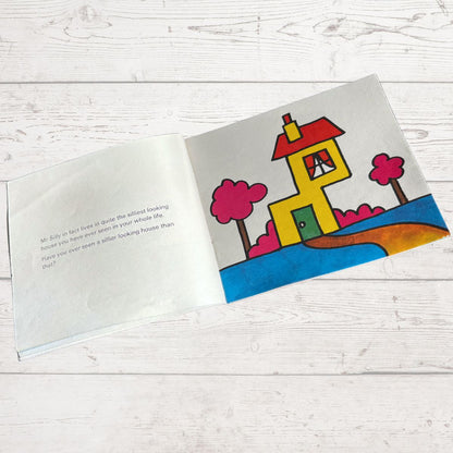 Open book with a colorful illustration of a house on a wooden surface
