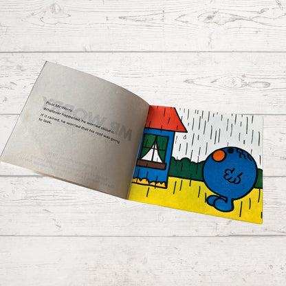 Open book with a colorful illustration of a blue character on a white wooden surface