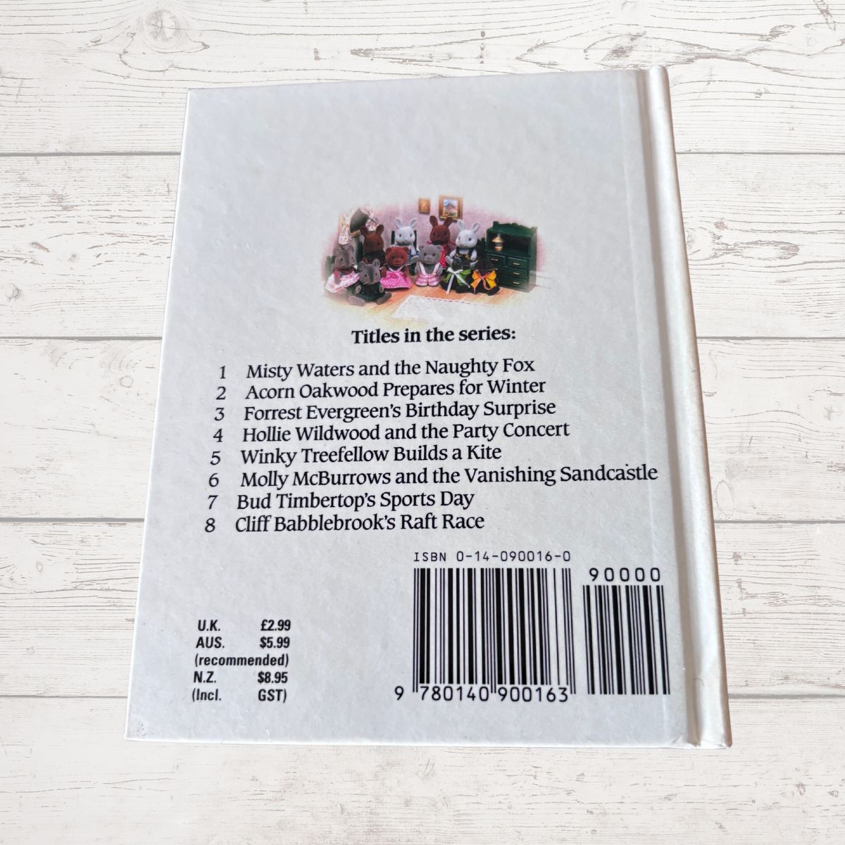 Back cover of a book with a list of titles and a barcode on a wooden surface