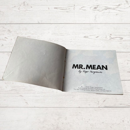 Open book with 'MR. MEAN' title on a light wooden surface