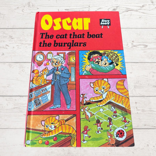 Book titled 'Oscar the cat that beat the burglars' with colorful illustrations on a wooden surface.